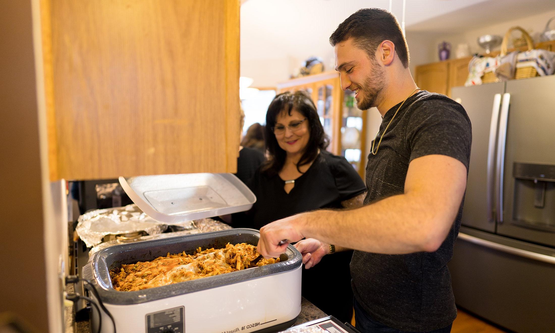 Two people putting food on their plate.